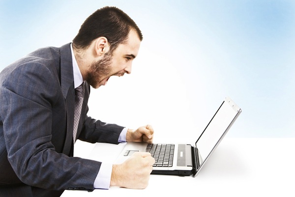 An angry man shouting at a laptop